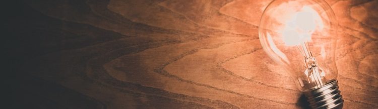 Close up of a lit light bulb on a wooden background