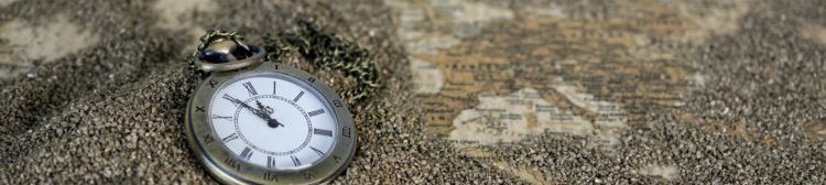 A pocket watch on a map, with grains of sand